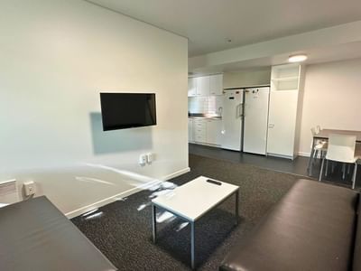 Black couches, white coffee table, and flat screen TV in a student accommodation.