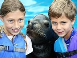 2 kids posing for a picture with a seal at Theater of the Sea near Bayside Inn Key Largo