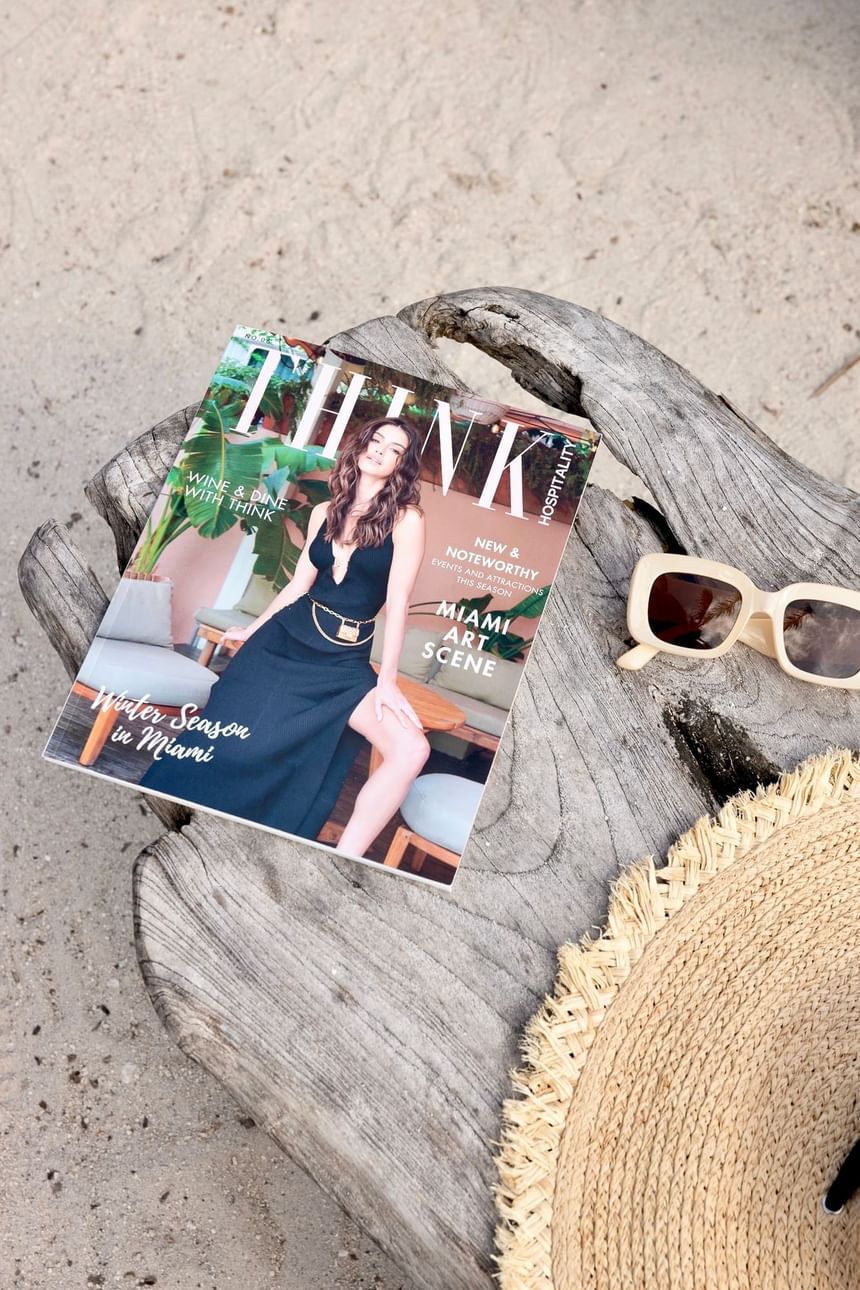 Magazine on a sandy beach with sunglasses and a hat at The Savoy On South Beach