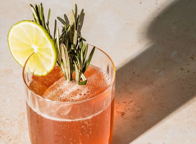 Cocktail topped with a citrus wheel slice & herb sprigs on a stone surface at Mountain View Grand Resort & Spa