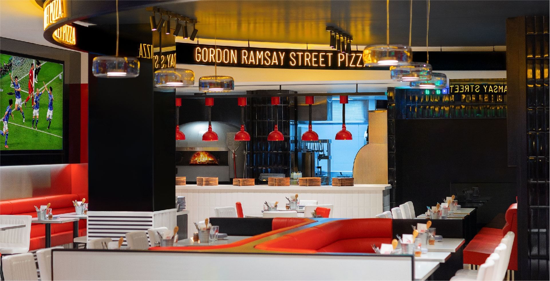 Gordon Ramsay Street Pizza interior with red seats, stylish décor, and sports showing on a big screen at Sunway Resort