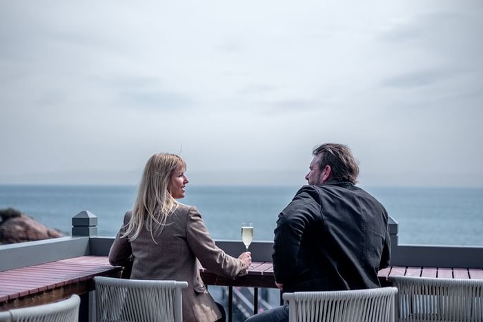 Couple enjoying meal while drinking wine overlooking the mountains at Freycinet Lodge