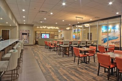 Elegant restaurant with a bar, high-top tables, and vibrant wall art at Buffalo Bill Village