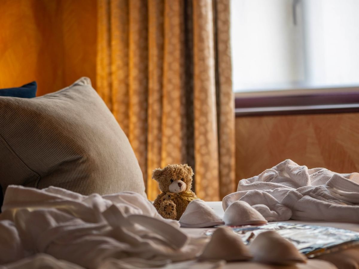 Baby cot with bedding and a teddy bear on a bed at The Capital Hotel, Apartments & Townhouse - London