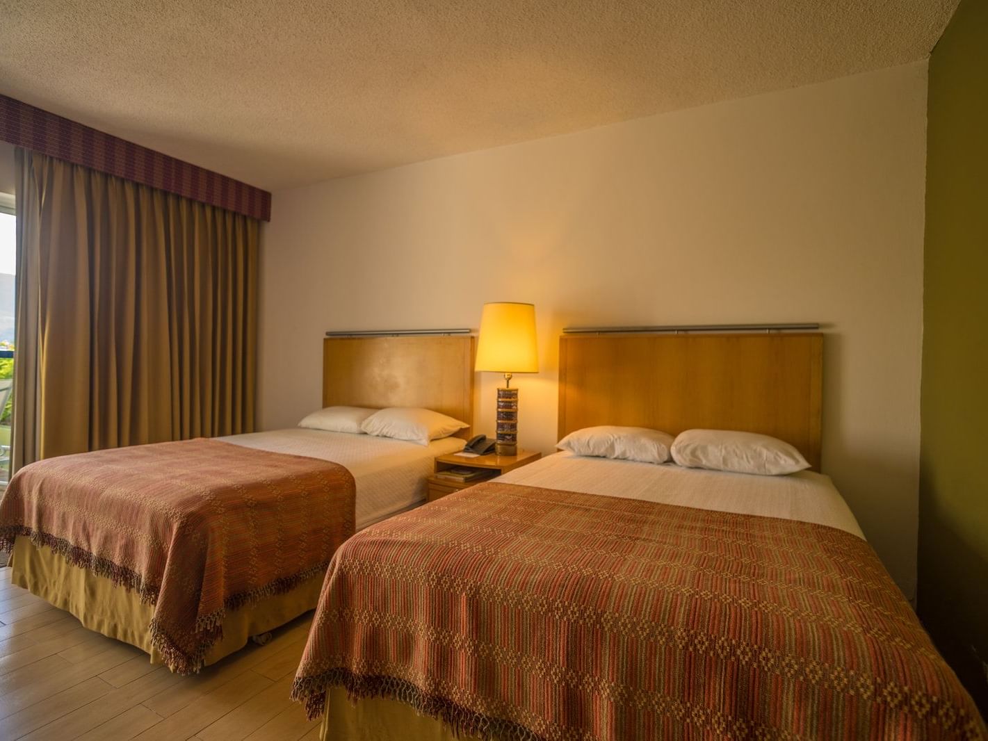 2 cozy beds and a side table in Standard Room with wooden floors at Porta Hotel del Lago