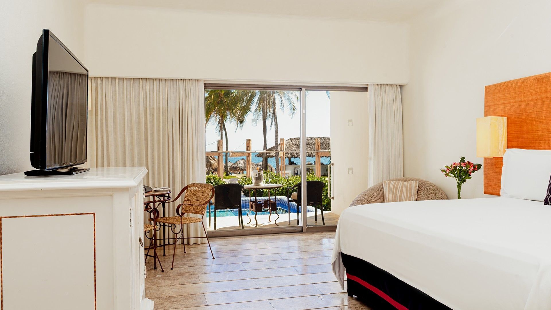 TV, lounge chair, & dining table by the bed in King Deluxe Private Pool with patio seating at Camino Real Zaashila Huatulco