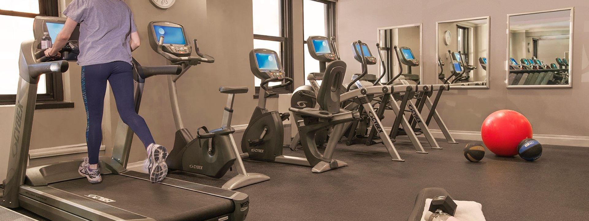 Woman running on a treadmill in a hotel fitness center with workout machines at Warwick New York