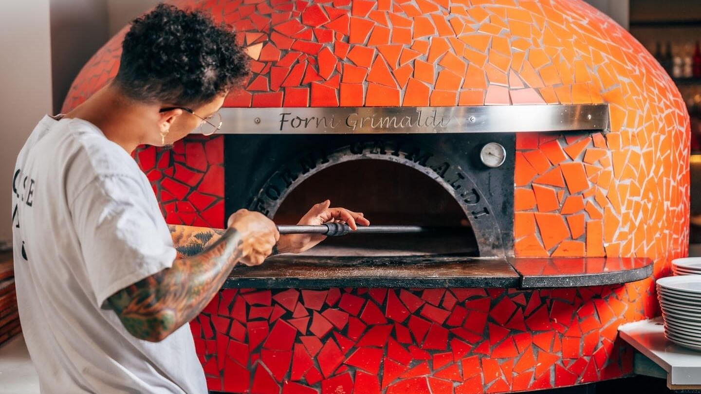 DeVita – Tastes of Napoli with a Chef working by a massive red-tiled pizza oven near Elysium Manly, a featured hotel in Manly