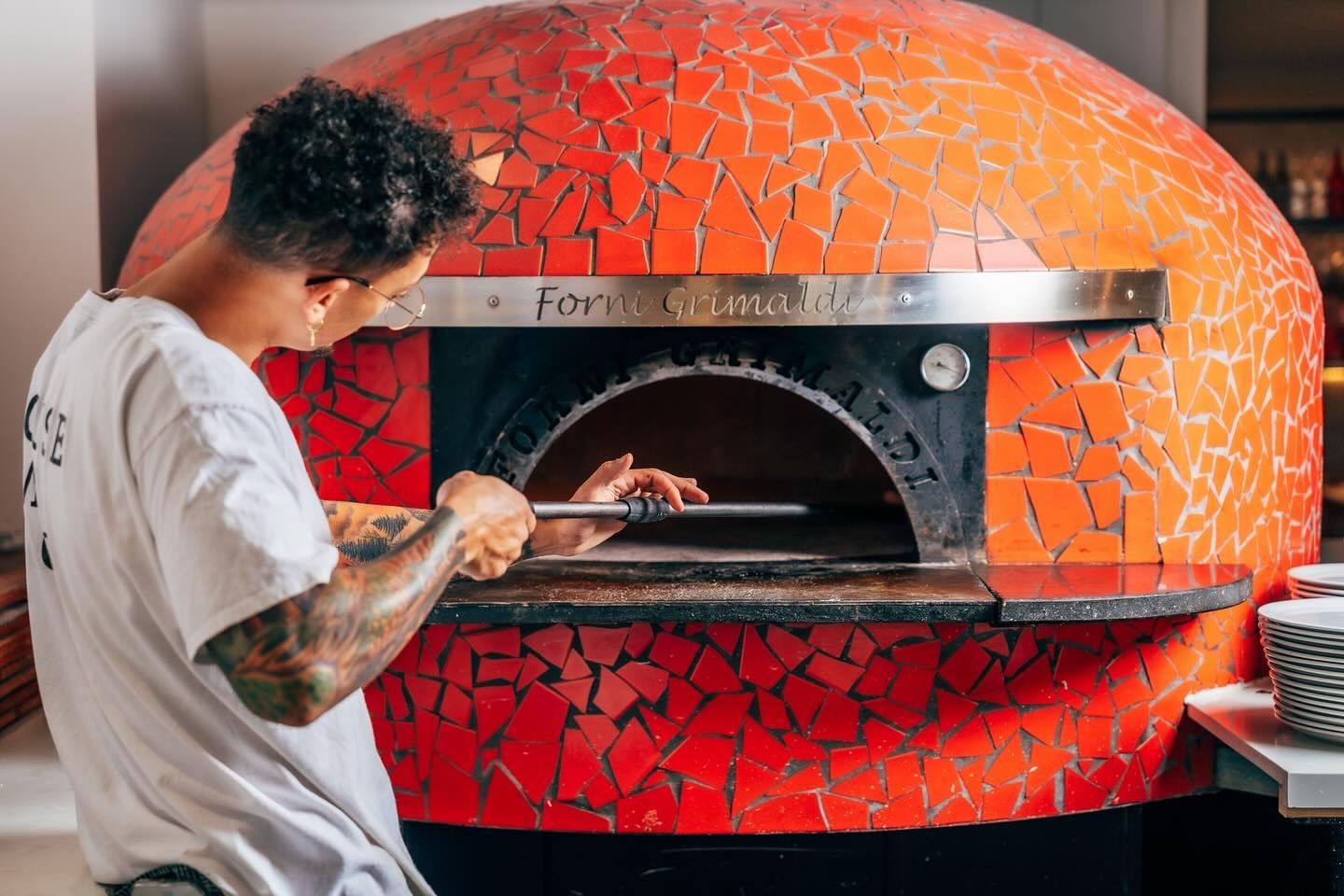 Forni Grimaldi at Elysium Hotels features a tattooed pizza chef using a wood-fired oven made with orange mosaic tiles