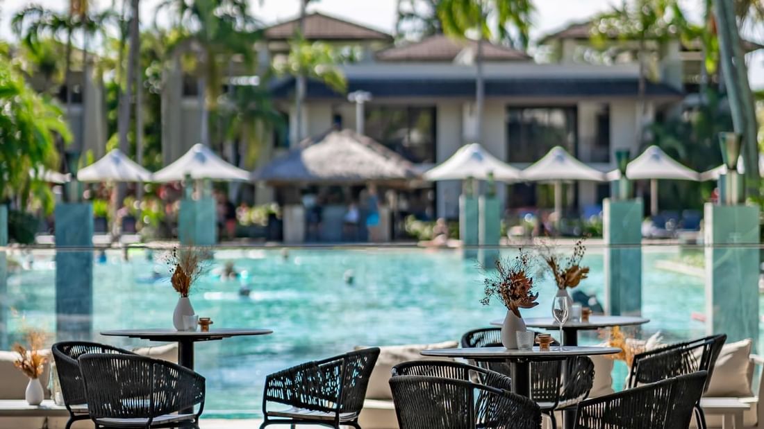 Outdoor poolside seating with vases on tables in Lagoon View Terrace at Pullman Port Douglas