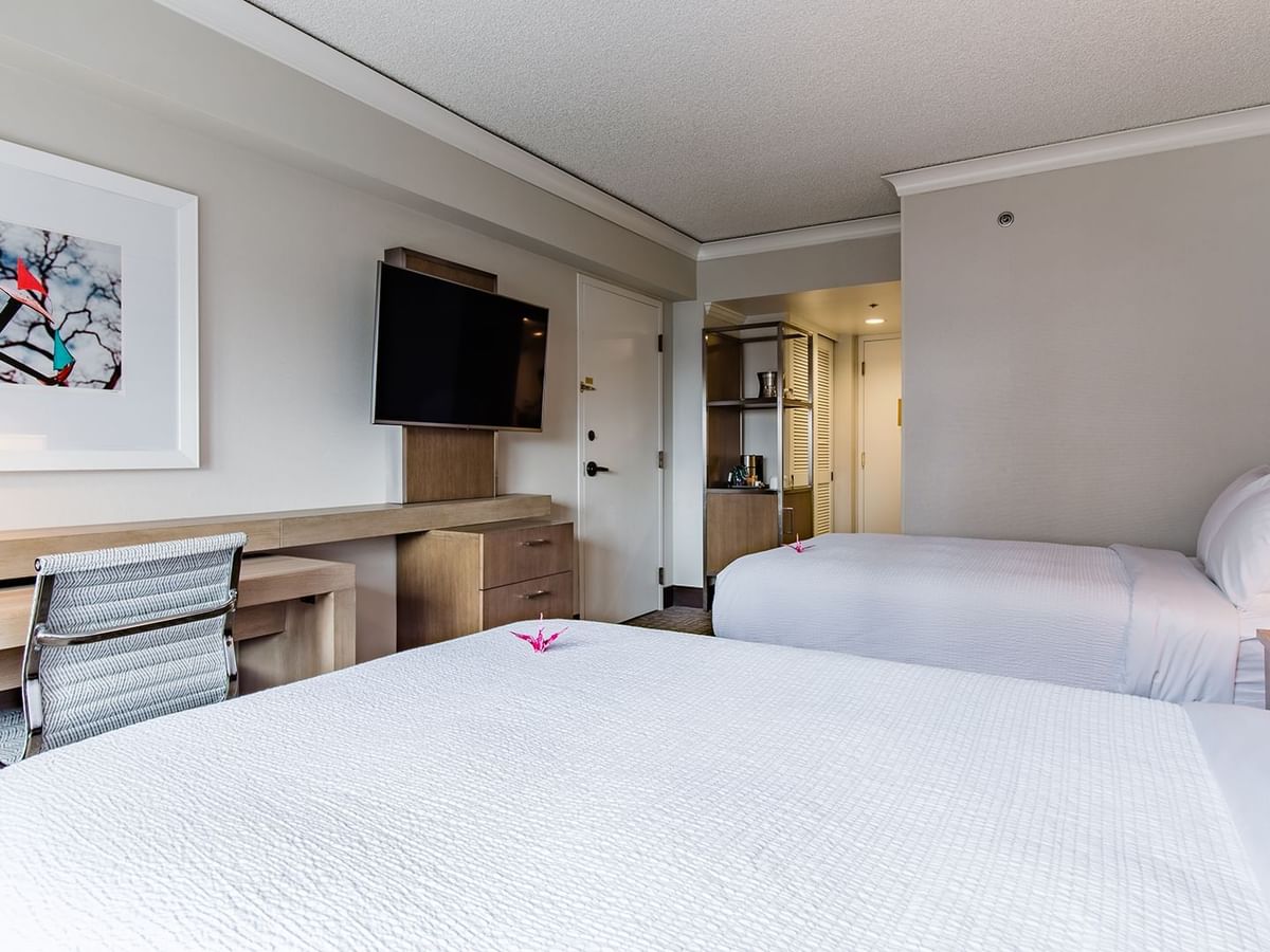 Hotel guestroom with two beds, TV, and desk