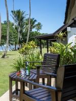 Ocean View Villa features Wooden chairs by a small table on a tiled patio under tall palm trees at Tambua Sands Beach Resort