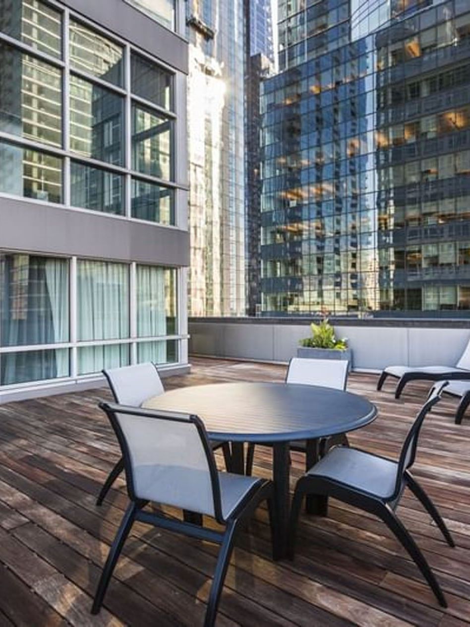 Outdoor wooden deck with dining setup and lounge chairs at Warwick Le Crystal Montreal.