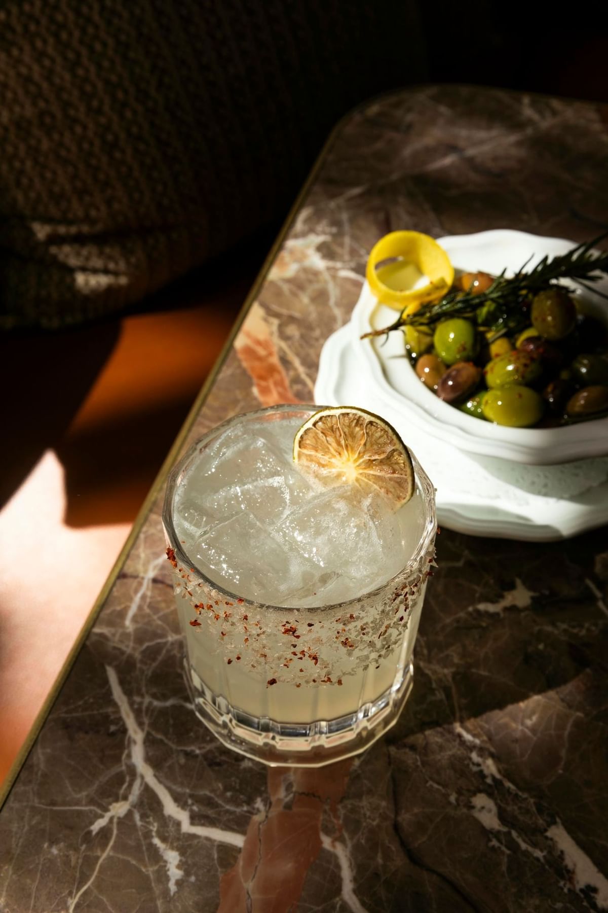Close-up of a refreshing cocktail with lime, olives, and lemon at Bar Remi in Granduca Houston