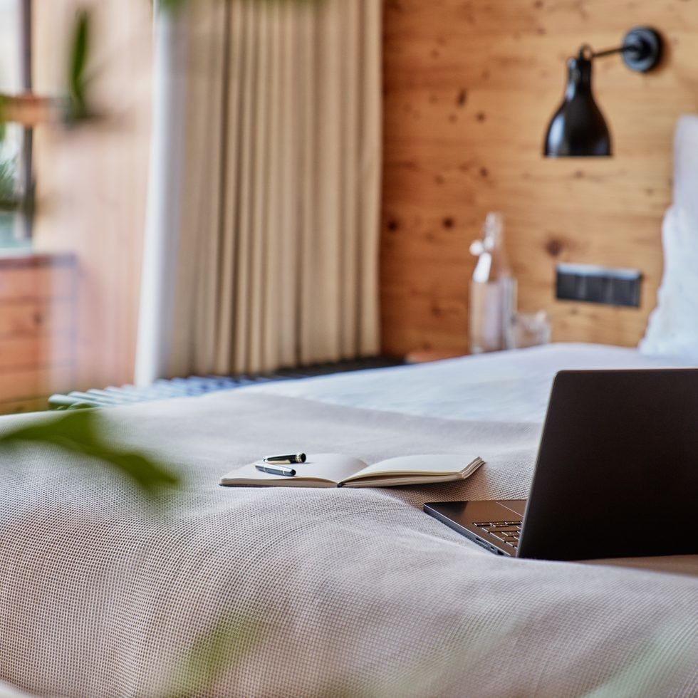 Laptop und Notizbuch auf einem Bett in einem gemütlichen Zimmer