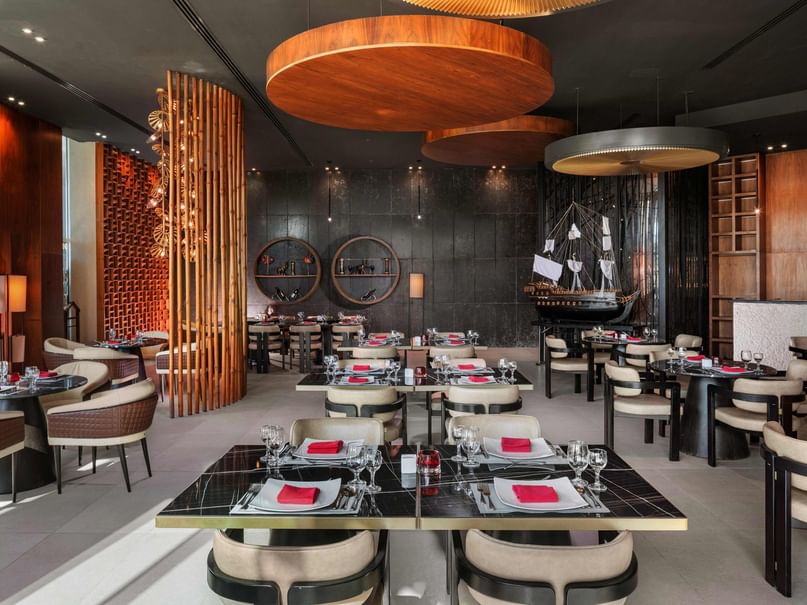 Elegant restaurant interior with round wooden tables, modern chairs, and decorative wooden elements on the walls and ceiling.