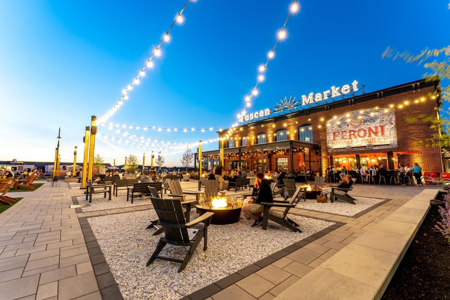 People hanging out in the patio area of illuminated Tuscan Market near The Artisan Hotel at Tuscan Village