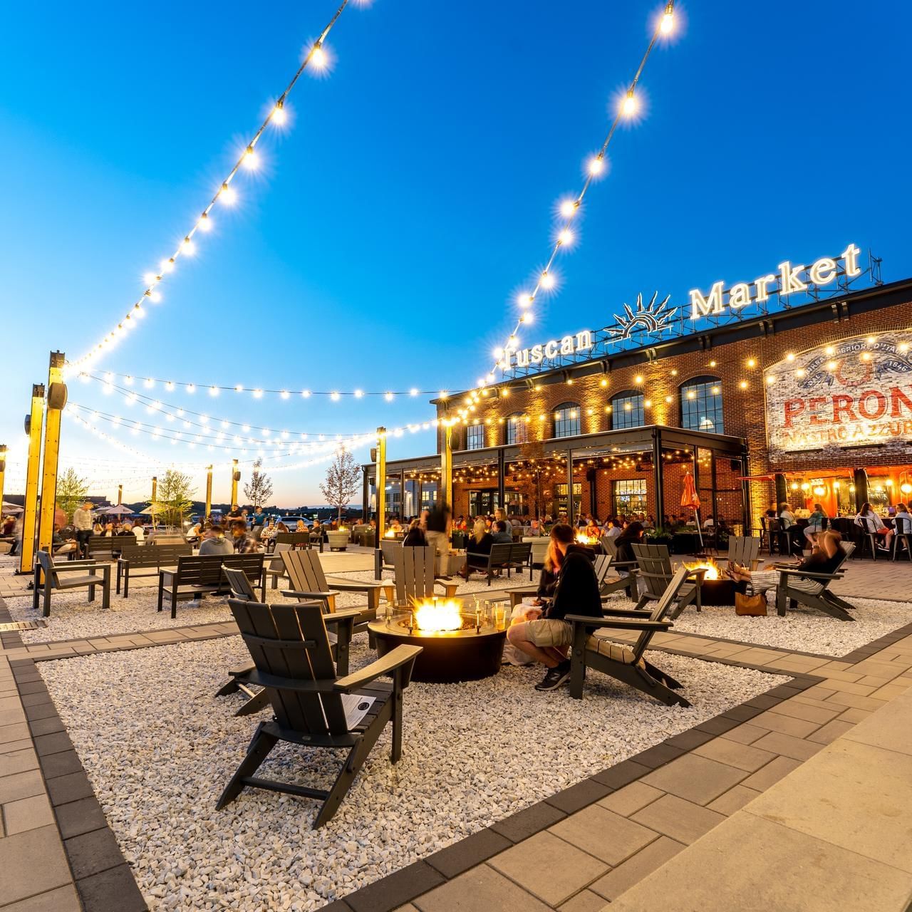 People lounging by the open space in illuminated Tuscan Market near The Artisan Hotel at Tuscan Village