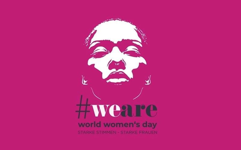 Grafische Illustration eines weiblichen Gesichts auf pinkem Hintergrund mit dem Schriftzug „#weare world women’s day – starke Stimmen, starke Frauen“.