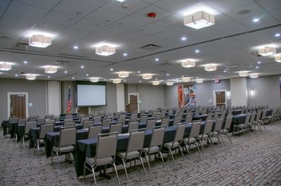 Spacious conference room with rows of tables, chairs, and a large projection screen at Buffalo Bill Village