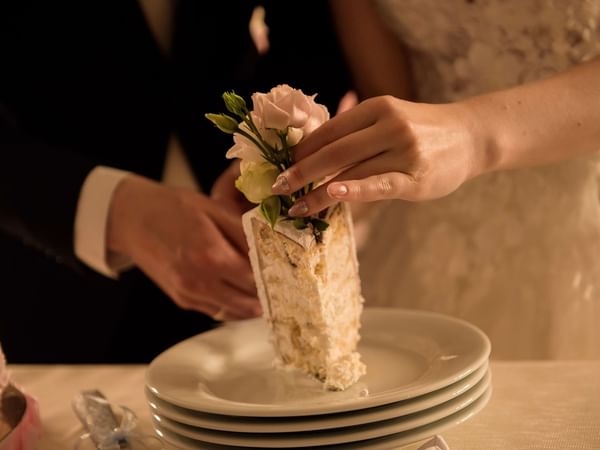 Close-up of a wedded couple serving the cake at Warwick Melrose