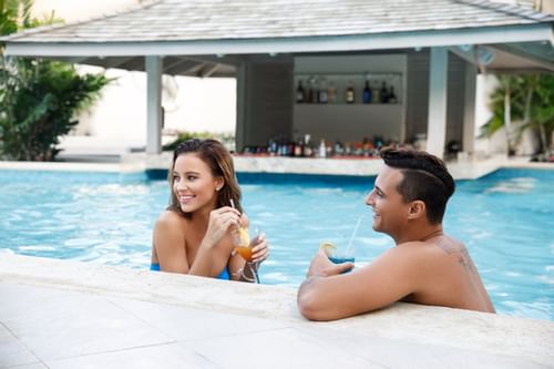 A couple spending time in the pool by the bar at Sugar Bay