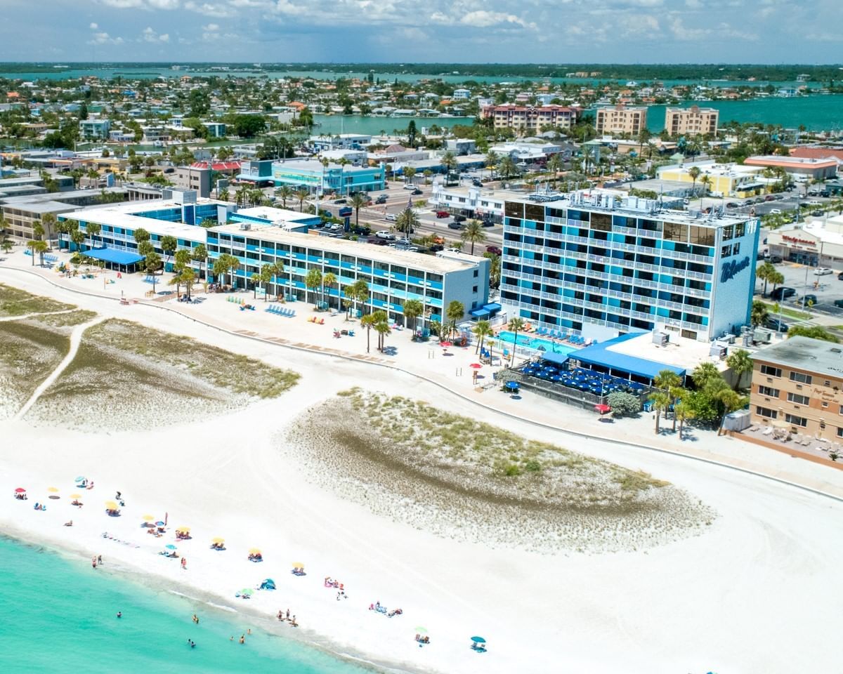 An aerial view of a beachfront resort with a pool and palm trees.