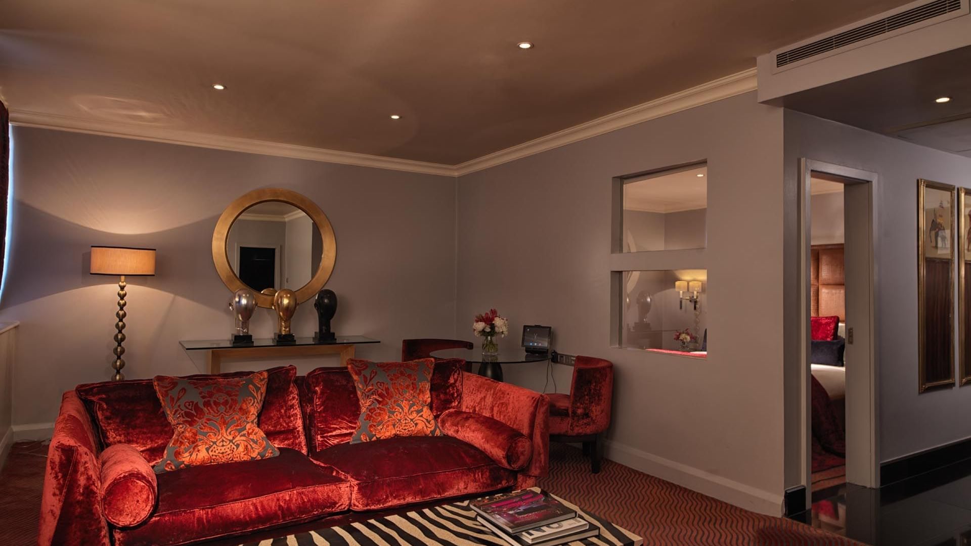 Luxurious Studio Suite living room at The May Fair Hotel featuring a red velvet sofa and decorative lamps