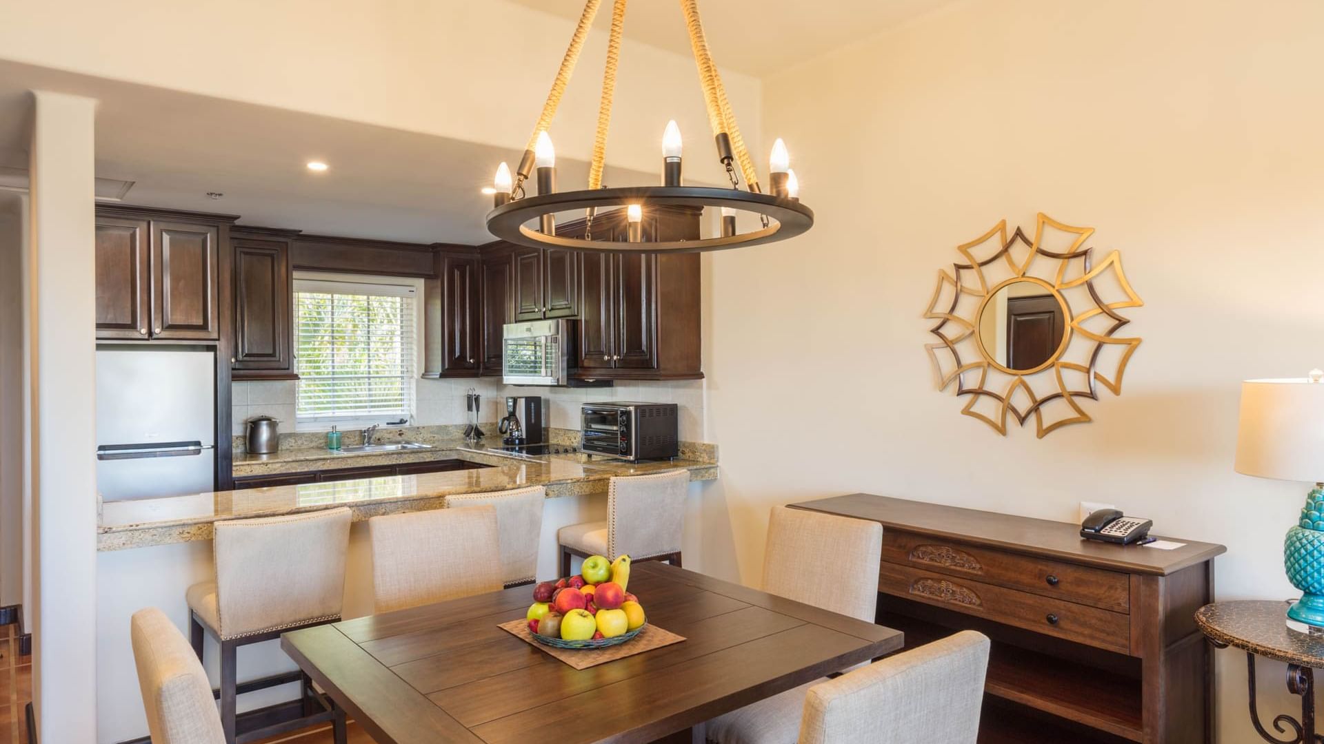 Charming dining area with chandelier full kitchen and wooden accents in the One Bedroom Villa at Hacienda Del Mar Los Cabos.