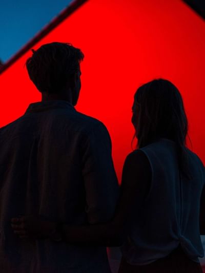 Couple watching red screen at dusk with water in background for Westpac OpenAir Cinema.