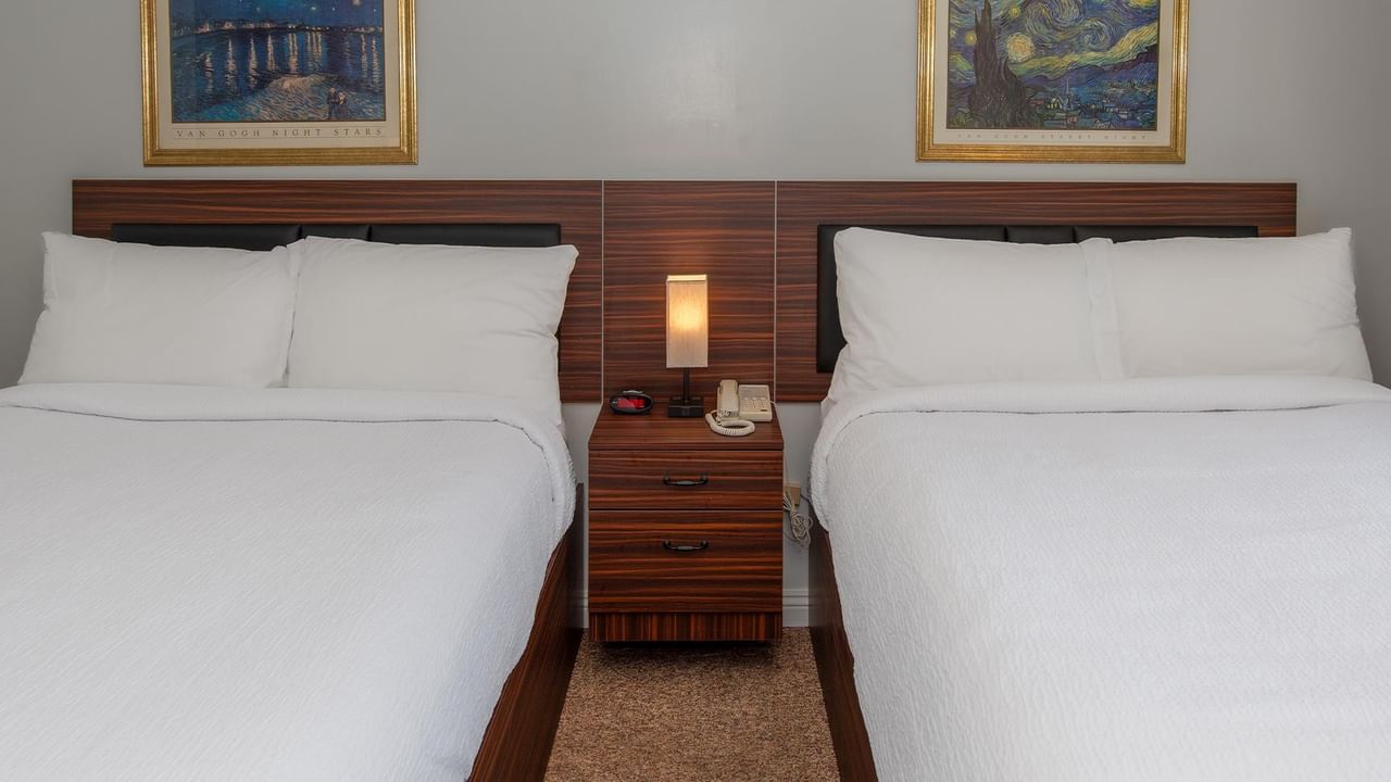 room with two queen beds, white bedding and a nightstand between them at Coast Whitecourt Hotel