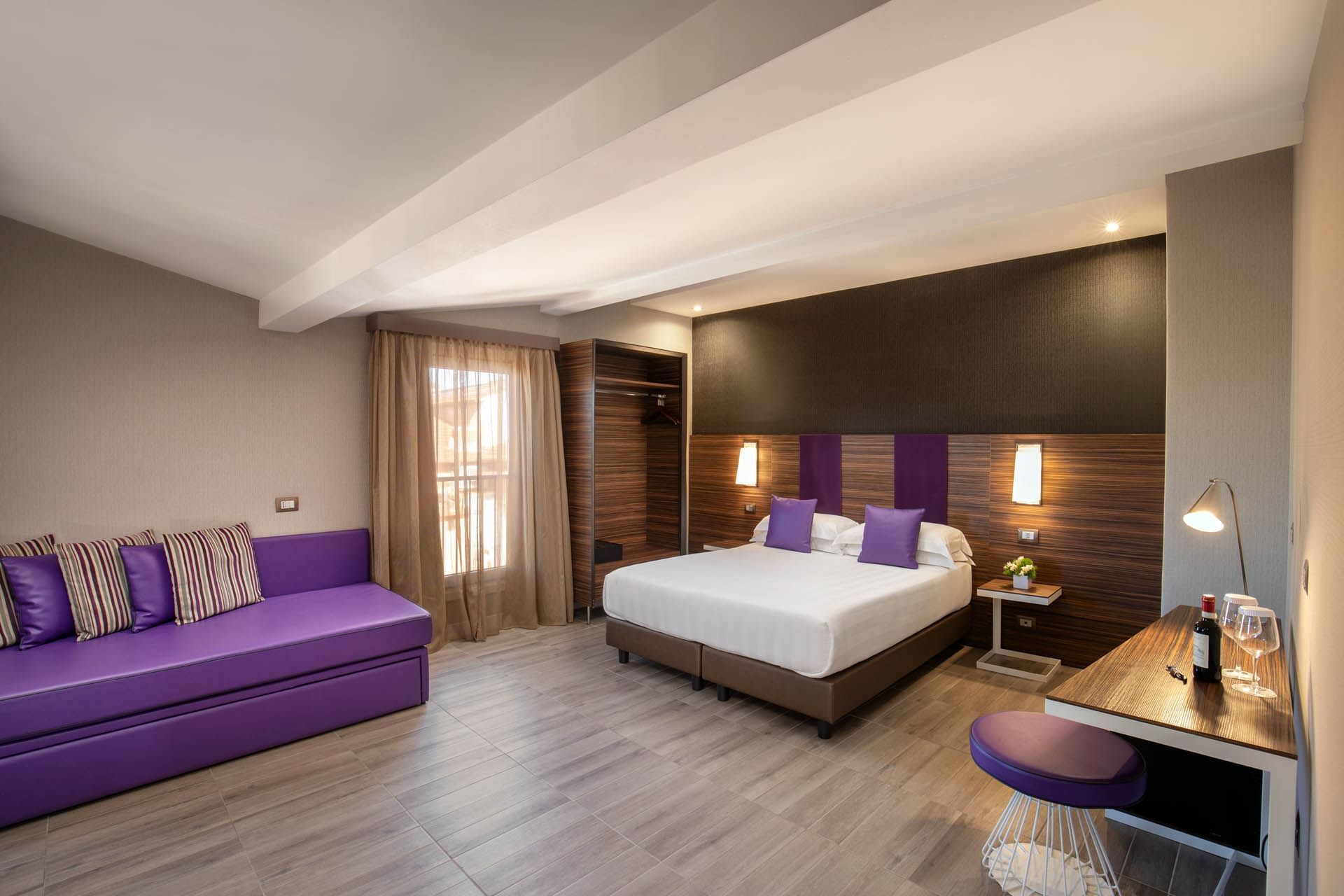 The Republic View Suite featuring a double bed, purple accents, a sofa, and natural light from window at The Republic Hotel