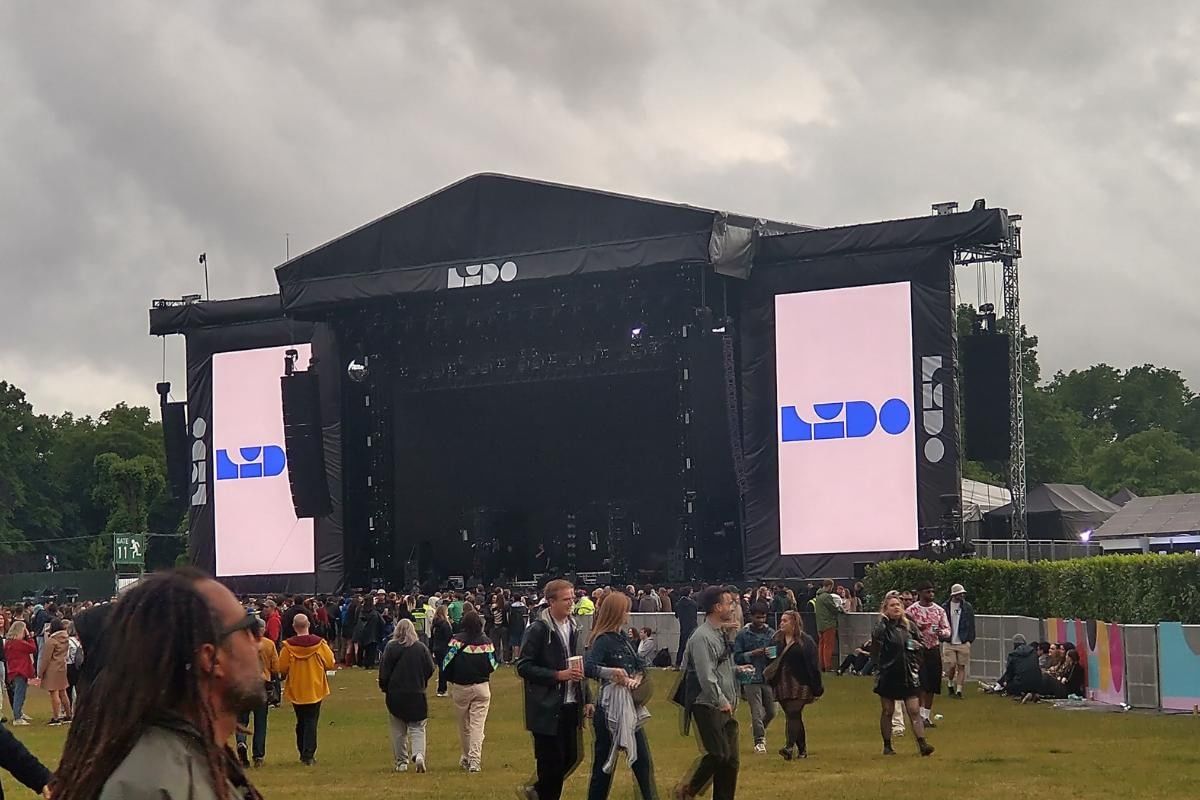 Outdoor music festival scene at Lido Festival near in London, showing an empty main stage and attendees