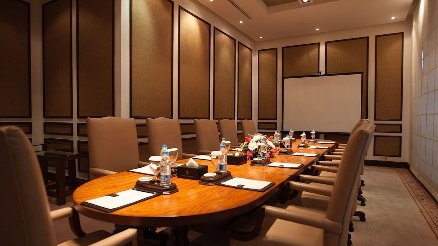 Wooden conference table with tan leather chairs and floral centerpiece in a private meeting room at Serena Hotels & Resorts