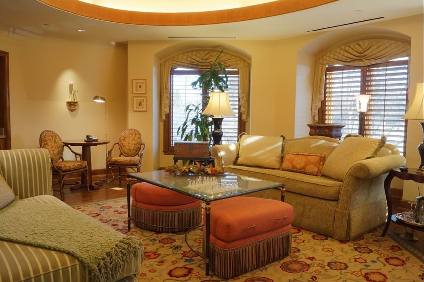 Cozy living room featuring striped sofa, plush pink ottomans, floral rug at The Rose Hotel