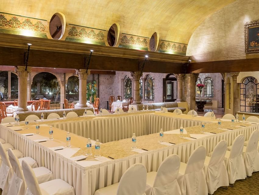 Salón Los Murales with a vaulted ceiling, stone pillars, and white seat covers at Quinta Real Aguascalientes