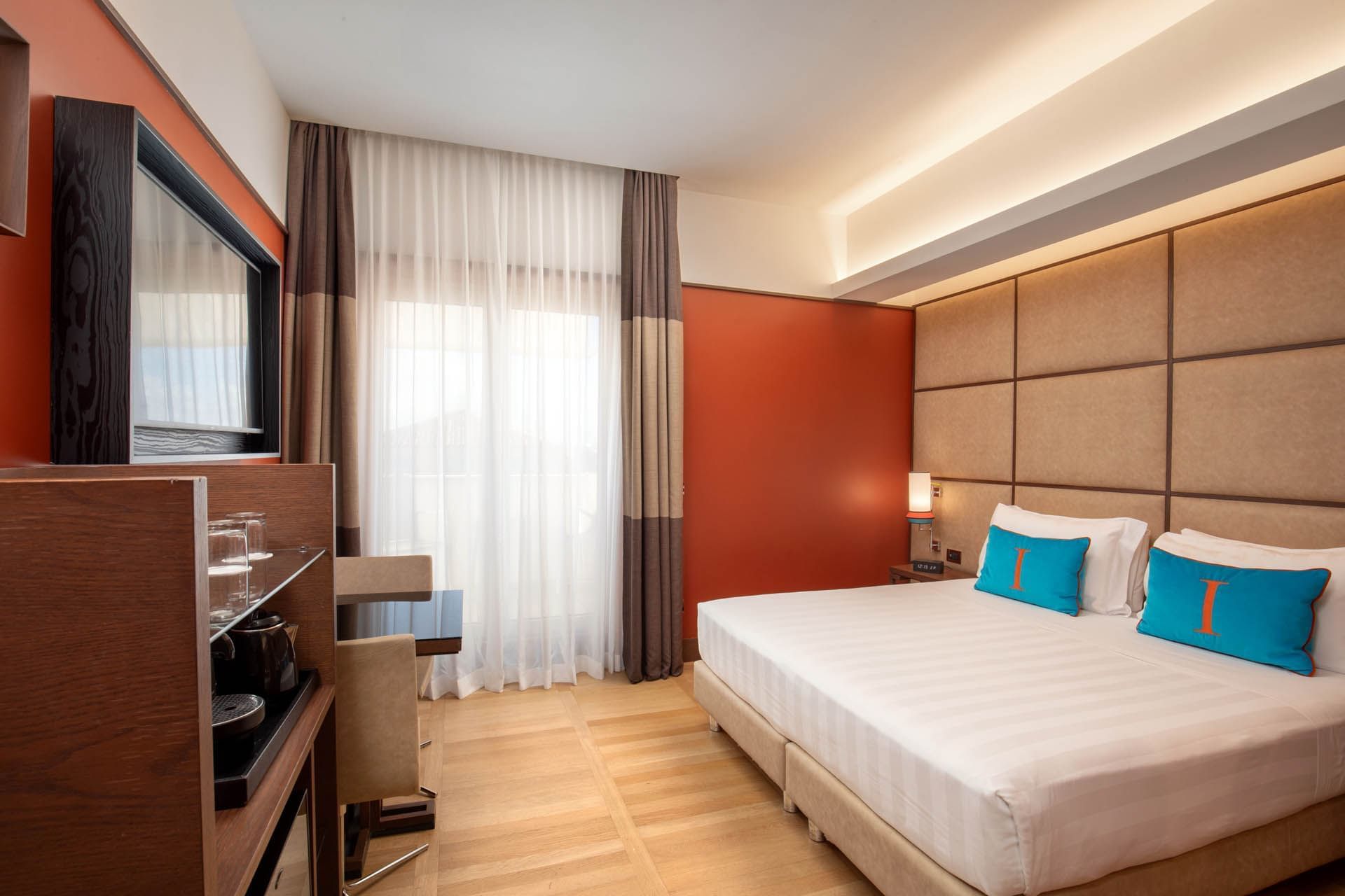 Cozy Superior Room with balcony, king bed, TV, seating, mini-fridge, and curtained windows at The Independent