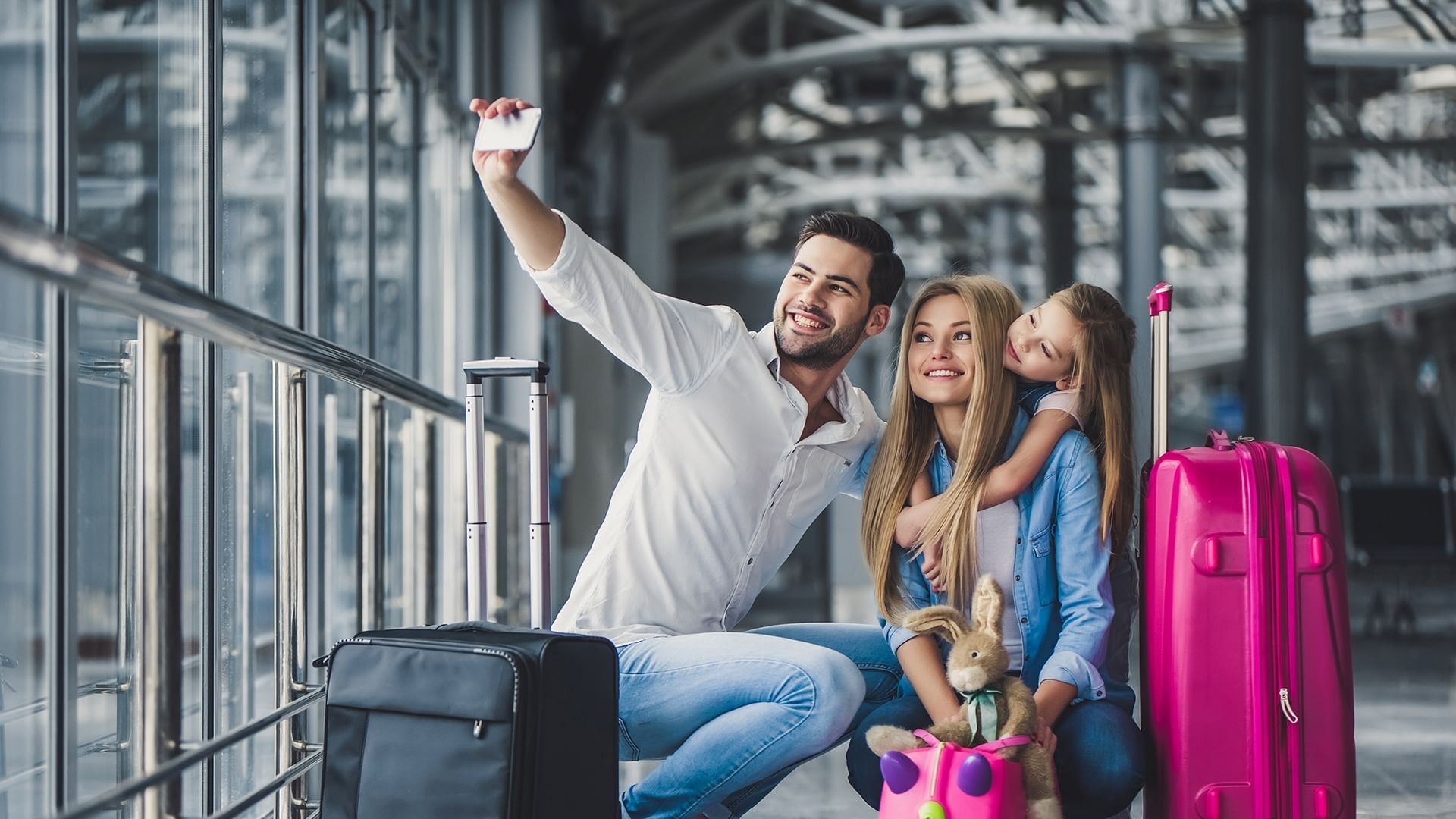 Father taking selfie with wife and daughter in airport with lugg