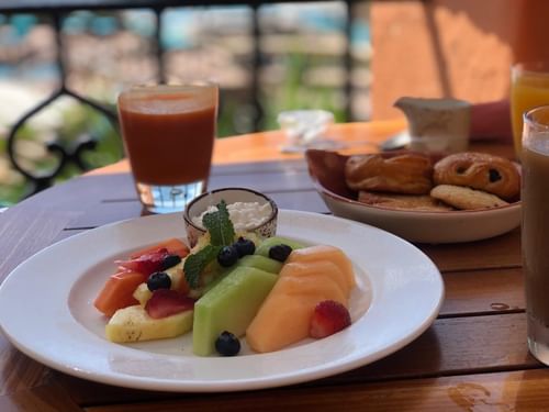 Tomates restaurant breakfast on a table with a fruit plate and pastries with an outdoor view at Hacienda del Mar Los Cabos.