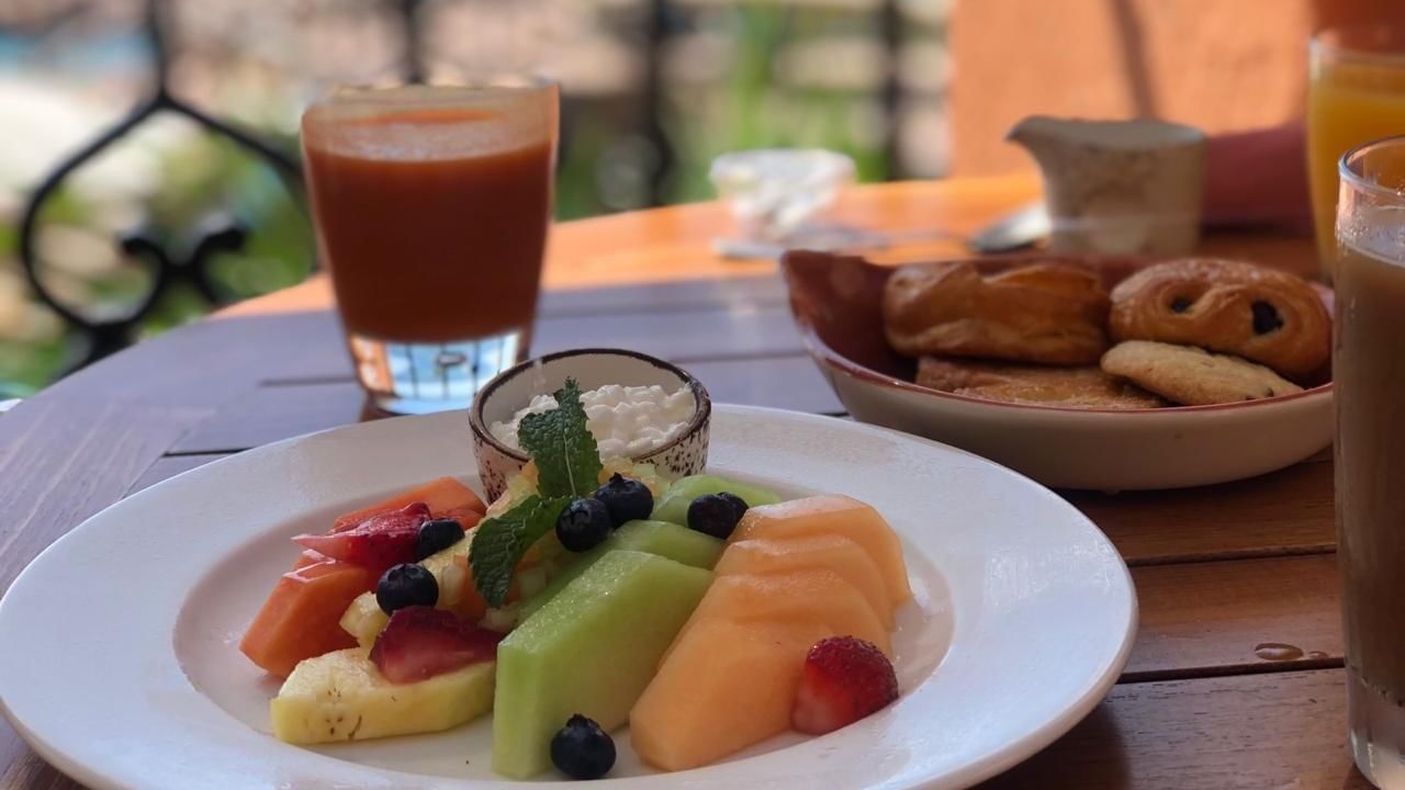 Tomates restaurant breakfast on a table with a fruit plate and pastries with an outdoor view at Hacienda del Mar Los Cabos.