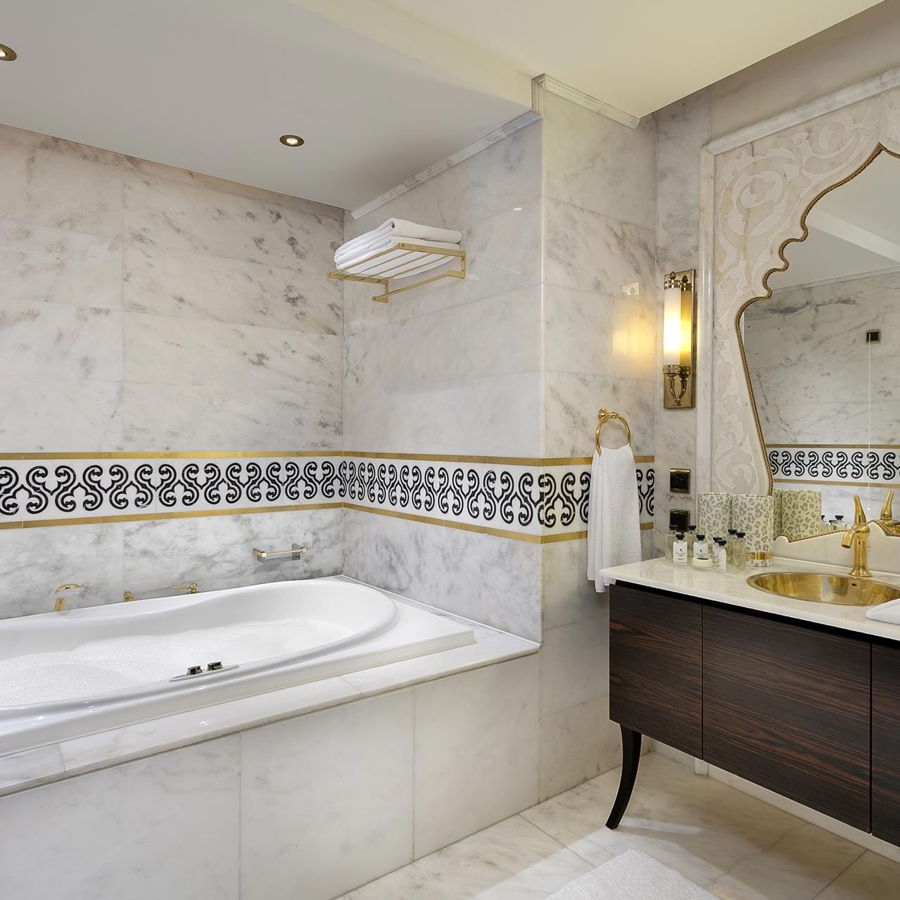 Ванная комната королевского двухуровневого люкса с большой ванной, мраморными поверхностями, декоративным зеркалом и деревянным туалетным столиком