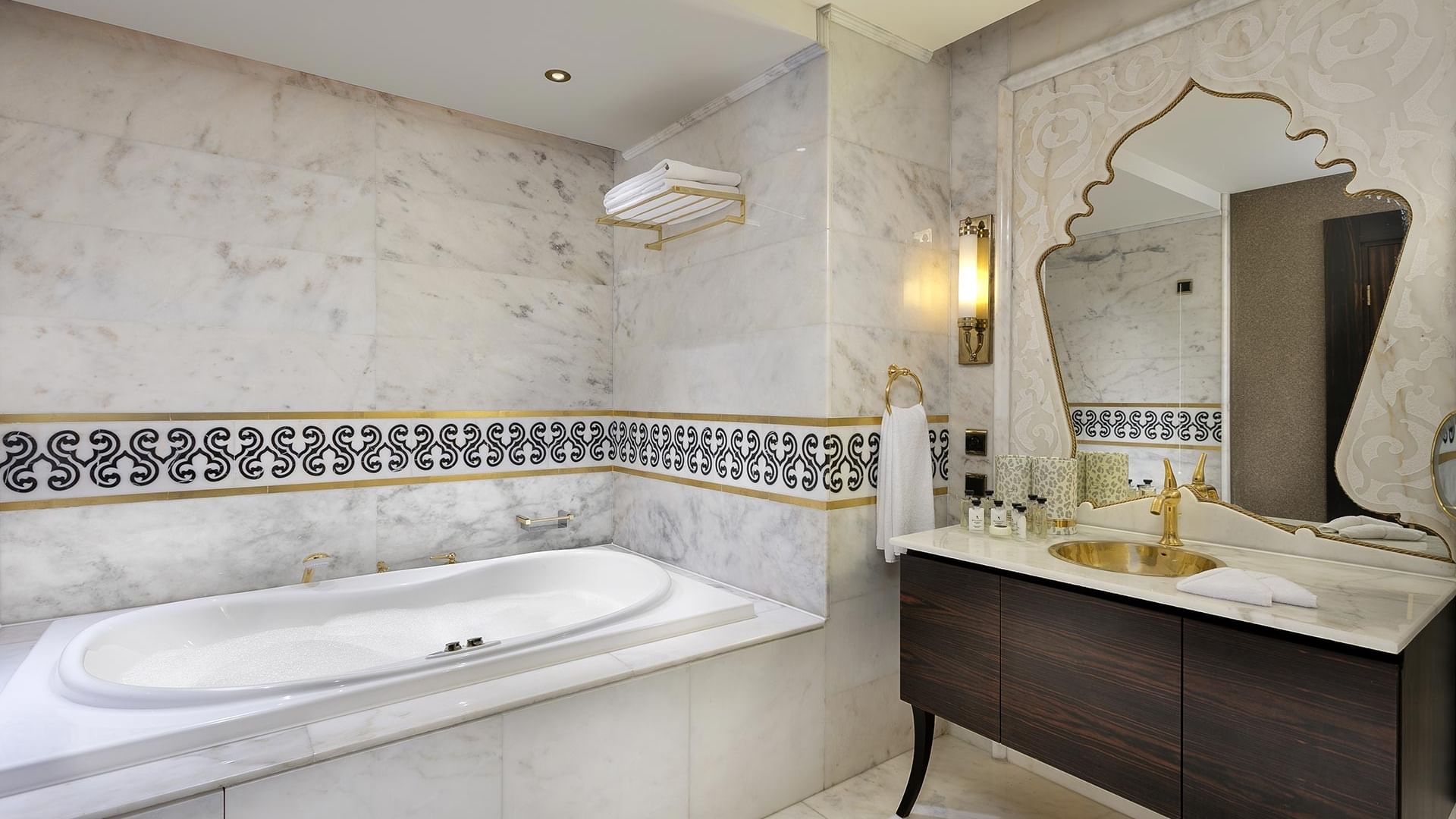 Ванная комната королевского двухуровневого люкса с большой ванной, мраморными поверхностями, декоративным зеркалом и деревянным туалетным столиком