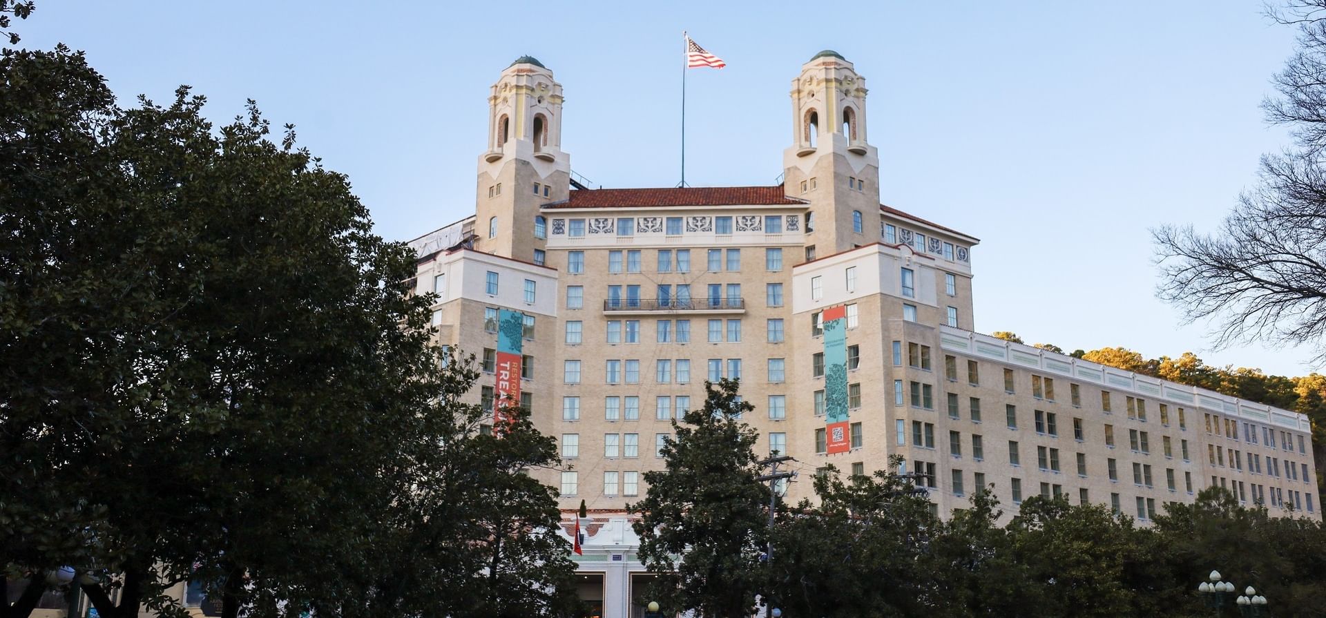 Historic facade of Arlington Resort Hotel & Spa with twin towers and American flag above trees under a clear blue sky