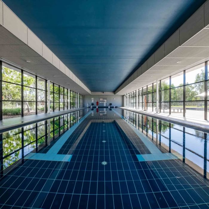 Indoor lap pool with reflective water, and large windows at Mercure Kooindah Waters