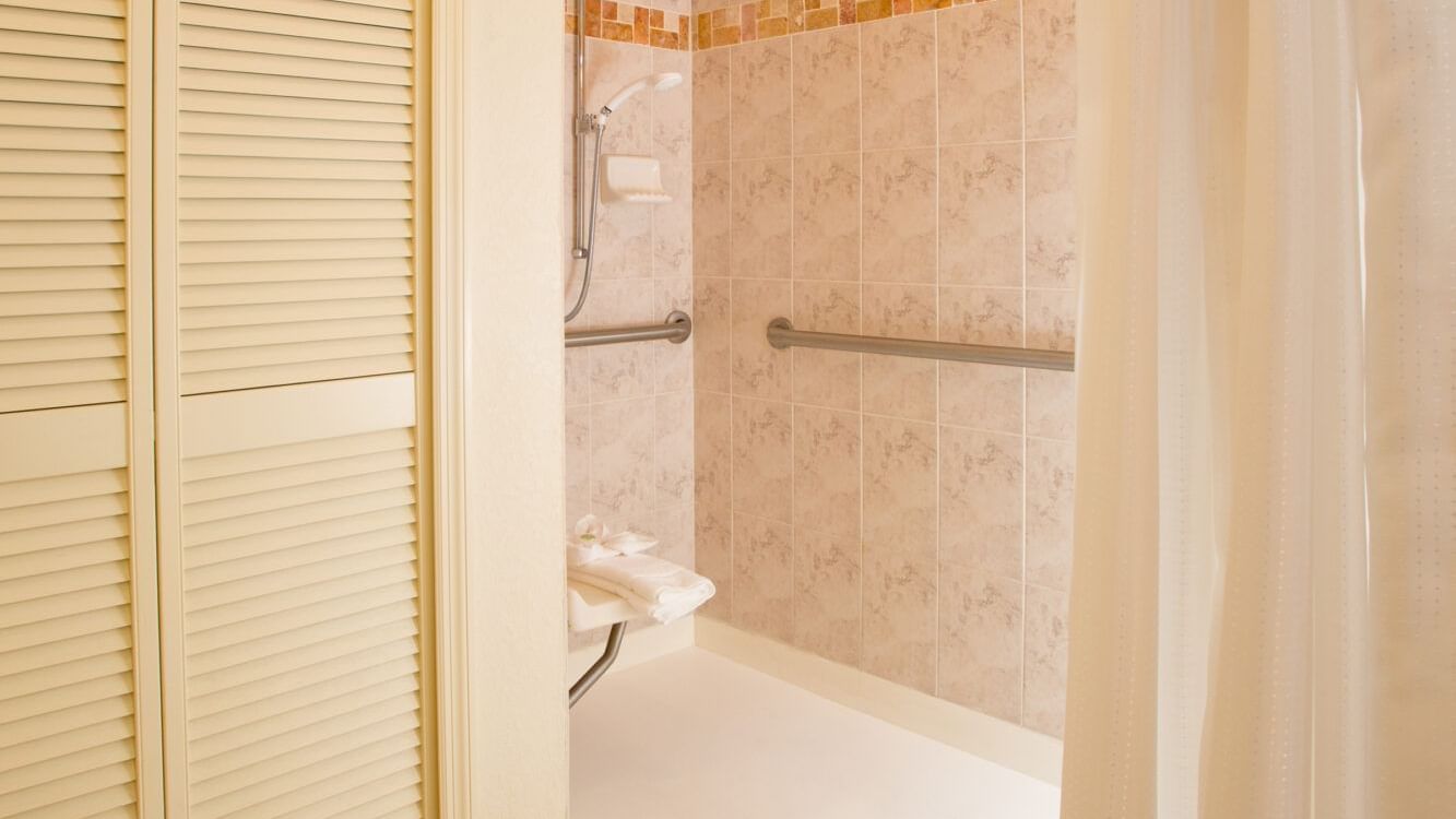 A bathroom with a tiled shower and grab bars.