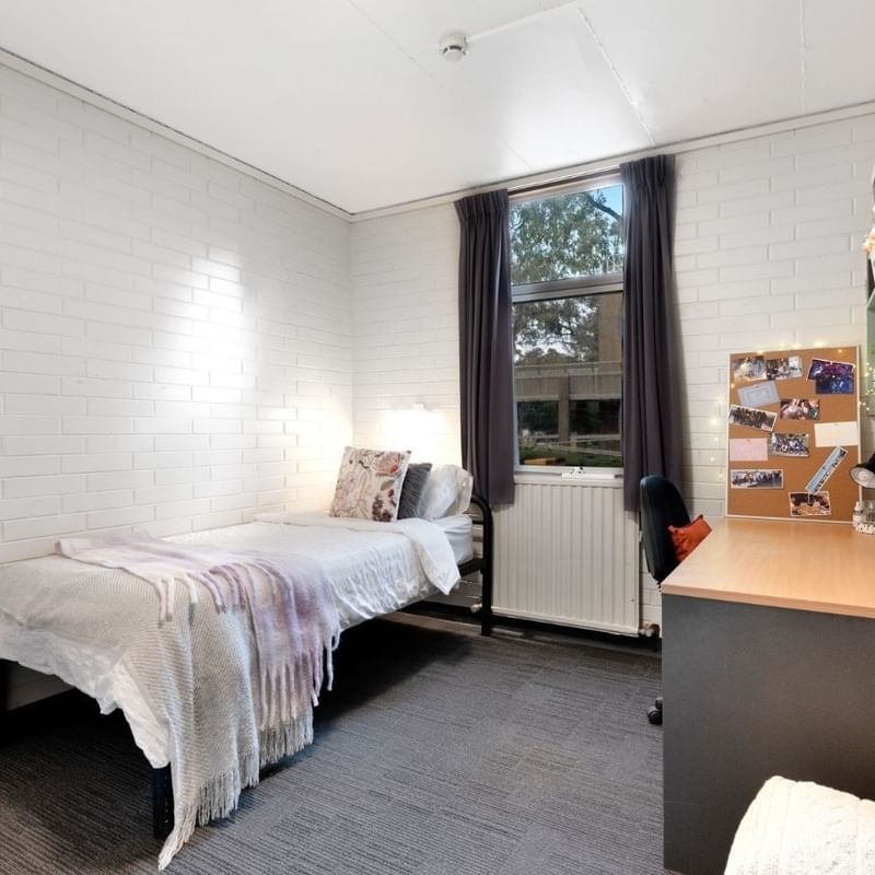 Small room with bed, desk, and window at La Trobe University - Glenn College.