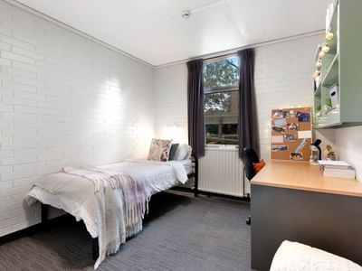 Small room with bed, desk, and window at La Trobe University - Glenn College.