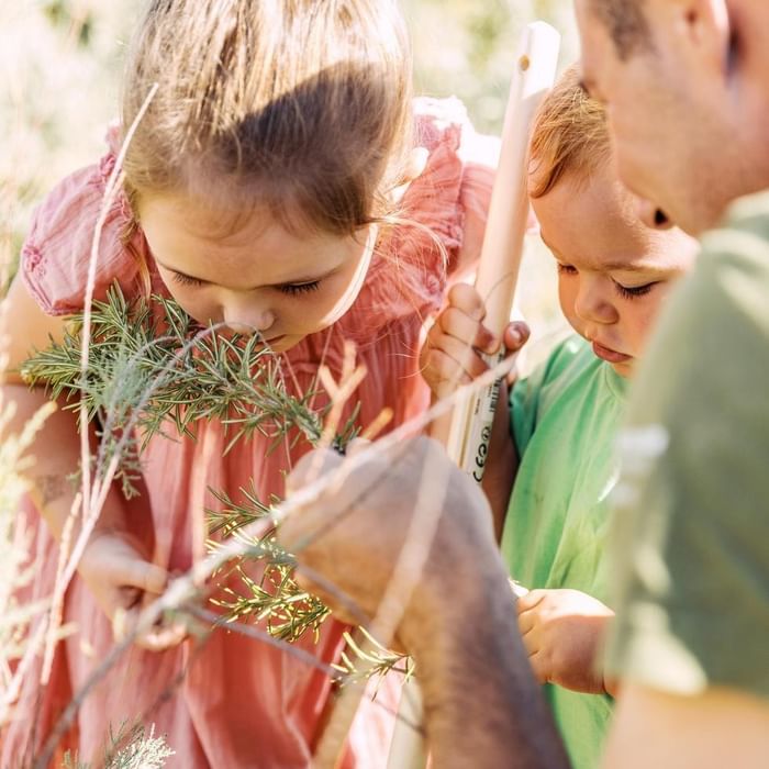 Two children smelling rosemary with their father at Falkensteiner Resort Lake Garda