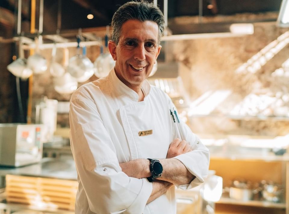 Chef sonriente con chaqueta blanca en una cocina profesional en Casa Santo Domingo