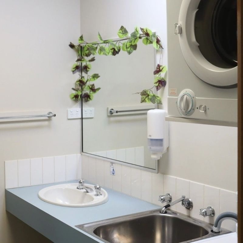 Bathroom with open shower stall, sink, mirror, and washing machine visible.